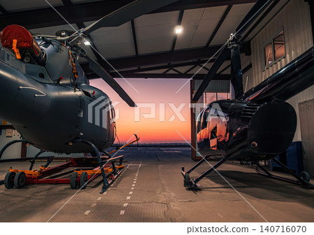 Helicopters parked in a hangar at sunset. 140716070