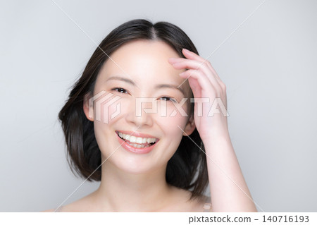 一位微笑的美麗女子，秀髮隨風飄揚；一張引人注目的美麗肖像，展現了她完美無瑕的肌膚和光澤亮麗的秀發，她面帶微笑，直視鏡頭。 140716193