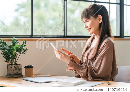 Middle-aged Asian women doing telework/nomad work in a cafe 140716414