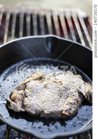 Searing Beef Steak In Cast Iron Skillet, Beautiful natural harvest for culinary documentary, organic food conservation, traditional local kitchen lifestyle and nutrition environment. Searing Beef Steak In Cast Iron Skillet, Beautiful natural harvest for culinary documentary, organic food conservation, traditional local kitchen lifestyle and nutrition environment. 140716578