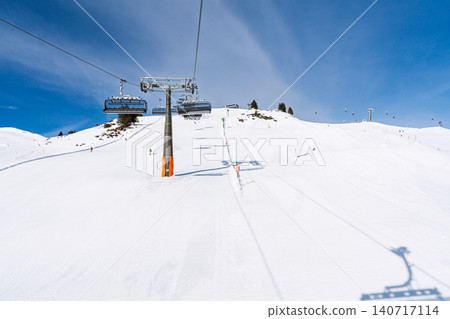 Ski lift over snowy slopes in Saalbach Hinterglemm, Austria, during a bright winter ski day 140717114