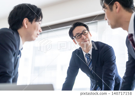 Three businessmen in suits are seriously exchanging opinions in a conference room. Three businessmen in suits are seriously exchanging opinions in a conference room. 140717158