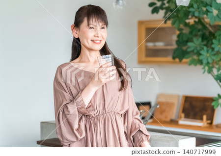 Middle-aged Asian woman hydrating in the kitchen 140717999