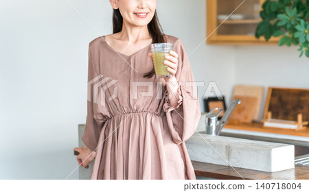 Middle-aged Asian woman drinking smoothie, vegetable juice in the kitchen Middle-aged Asian woman drinking smoothie, vegetable juice in the kitchen 140718004