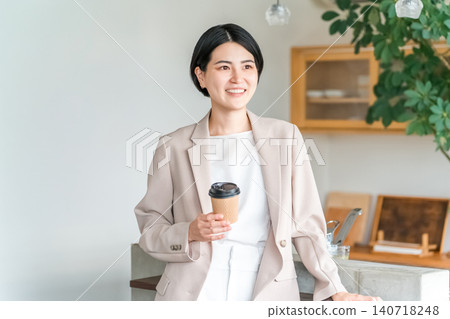 Young Asian business woman in a suit holding a paper cup of coffee Young Asian business woman in a suit holding a paper cup of coffee 140718248