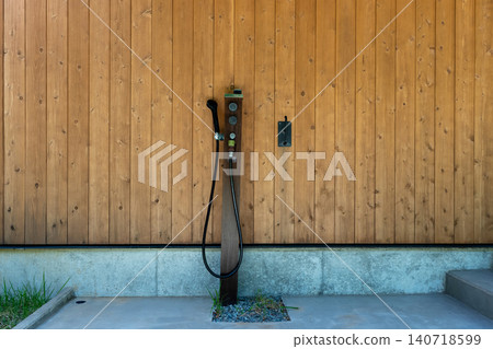 A modern outdoor shower installed on a wood-grain exterior wall. A modern outdoor shower installed on a wood-grain exterior wall. 140718599