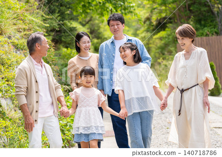 A smiling three-generation family walking through the fresh greenery. A smiling three-generation family walking through the fresh greenery. 140718786