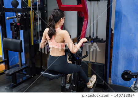 Asian woman exercising on seated row machine at gym for strength training Asian woman exercising on seated row machine at gym for strength training 140718884