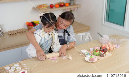 Asian grandmother and granddaughter rolling dough together in kitchen for family baking Asian grandmother and granddaughter rolling dough together in kitchen for family baking 140718936