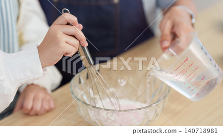 Close up of hands whisking ingredients and pouring water into bowl for baking Close up of hands whisking ingredients and pouring water into bowl for baking 140718981