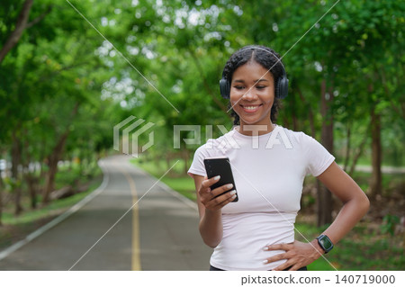Black woman with headphones using smartphone on park path Black woman with headphones using smartphone on park path 140719000