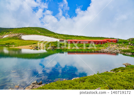 在晴朗的夏日,白馬禦池山屋的紅色屋頂和夏日的天空美麗地倒映在白馬禦池湖的湖面上,形成了一幅令人驚嘆的鏡面景象。 在晴朗的夏日,白馬禦池山屋的紅色屋頂和夏日的天空美麗地倒映在白馬禦池湖的湖面上,形成了一幅令人驚嘆的鏡面景象。 140719172