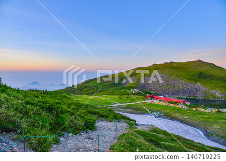 A view of Hakuba Oike Lake and the colorful campsite during the magic hour, seen from near Raicho-zaka on a summer evening. A view of Hakuba Oike Lake and the colorful campsite during the magic hour, seen from near Raicho-zaka on a summer evening. 140719225