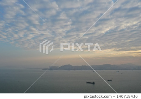 一張極簡風格的空拍照片，展現了黃昏時分平靜的海面和朦朧的海岸線。 140719436