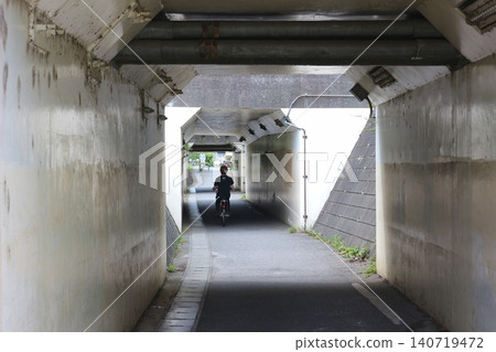 A narrow pedestrian tunnel and concrete walkway beneath the railway tracks. A narrow pedestrian tunnel and concrete walkway beneath the railway tracks. 140719472
