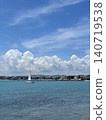Sailboat on turquoise sea photo with coastal town, dramatic white clouds and blue sky, peaceful summer travel landscape for seaside vacation, tourism, sailing, nature and marine design 140719538