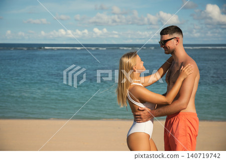 Couple stands on the beach by the water together Couple stands on the beach by the water together 140719742