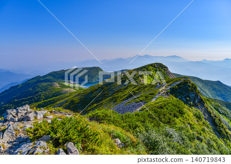 On a clear summer day, Hakuba Oike Lake and the distant, hazy Myoko landscape can be seen from the Northern Alps and the Hakuba mountain range. 140719843