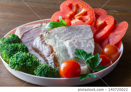 Baked HAM steaks lie on green lettuce leaves, cherry tomatoes and broccoli. Baked HAM steaks lie on green lettuce leaves, cherry tomatoes and broccoli. 140720022