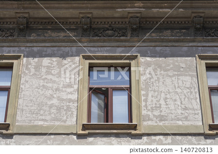 Old weathered building facade with classic windows and damaged plaster 140720813