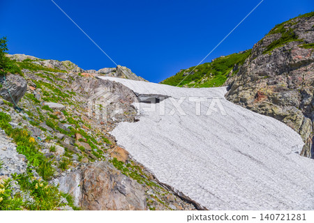 A clear summer day: The magnificent scenery of the upper part of the Hakuba Daisekkei snowfield, stretching out like a flowing stream between the rocky cliffs. 140721281