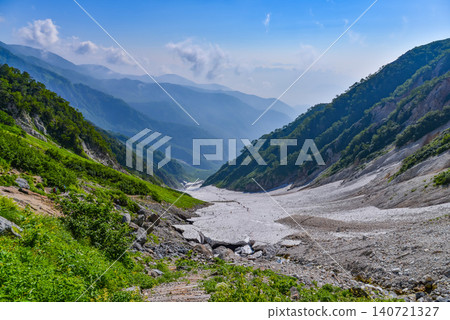 A clear summer day, a stream of hikers making their way across the Hakuba Daisekkei (Great Snow Valley) in the Northern Alps, and the magnificent scenery of the snowfield. 140721327