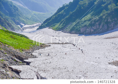 A clear summer day, a stream of hikers making their way across the Hakuba Daisekkei (Great Snow Valley) in the Northern Alps, and the magnificent scenery of the snowfield. 140721328