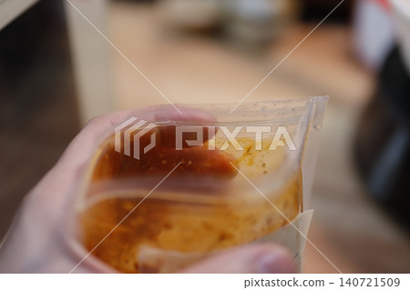 Hand Holding Sauce in Plastic Bag Close-up 140721509