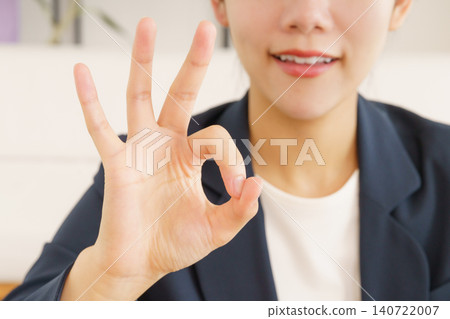 Close-up of a young Japanese woman in a suit making an OK sign. 140722007