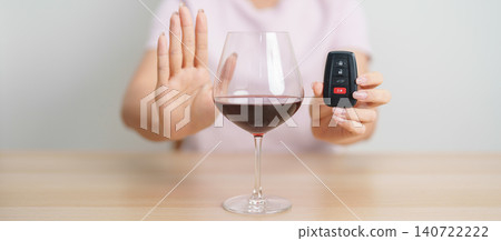 Responsible woman reject a drink before driving for road safety, woman making stop hand gesture to refuse a glass of Wine and car remote. Avoid drink and drive, Drunk Driving Law concept Responsible woman reject a drink before driving for road safety, woman making stop hand gesture to refuse a glass of Wine and car remote. Avoid drink and drive, Drunk Driving Law concept 140722222