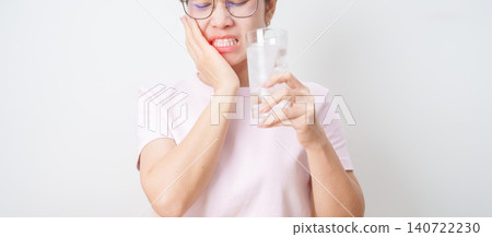 woman having toothache and pain after drink ice water for concept of Teeth Sensitive to Cold, Tooth Decay and Gum Disease, Grinding Teeth and Stress, Exposed Nerve Roots, Crack and Receding 140722230