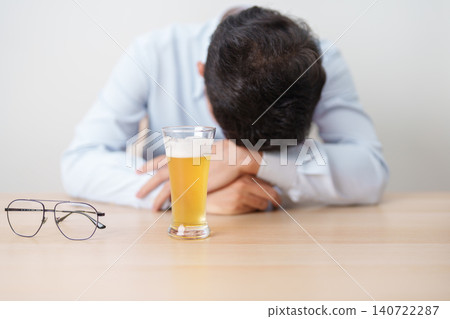 Stressed man drinking beer alone with problem. Exhausted drunk man looking stressed and sleepy. Alcohol addiction, Alcoholism, emotional distress and mental health concept Stressed man drinking beer alone with problem. Exhausted drunk man looking stressed and sleepy. Alcohol addiction, Alcoholism, emotional distress and mental health concept 140722287
