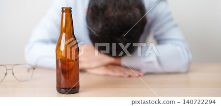 Stressed man drinking beer alone with problem. Exhausted drunk man looking stressed and sleepy. Alcohol addiction, Alcoholism, emotional distress and mental health concept Stressed man drinking beer alone with problem. Exhausted drunk man looking stressed and sleepy. Alcohol addiction, Alcoholism, emotional distress and mental health concept 140722294