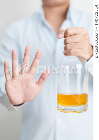 Man making stop hand gesture to refuse a bottle of whiskey, Healthy man say no to alcohol drink, stop alcoholism and addiction concept. Responsible man reject a drink before driving and quit booze Man making stop hand gesture to refuse a bottle of whiskey, Healthy man say no to alcohol drink, stop alcoholism and addiction concept. Responsible man reject a drink before driving and quit booze 140722314