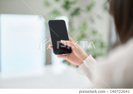 一位二十多歲的女性正在看她的智慧型手機。 一位二十多歲的女性正在看她的智慧型手機。 140722641