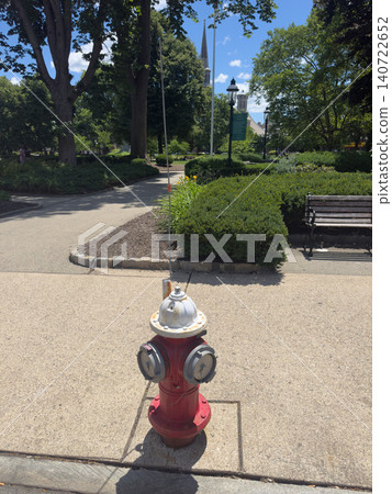 A close-up of a red and white fire hydrant standing on a sidewalk in a city park. A close-up of a red and white fire hydrant standing on a sidewalk in a city park. 140722652