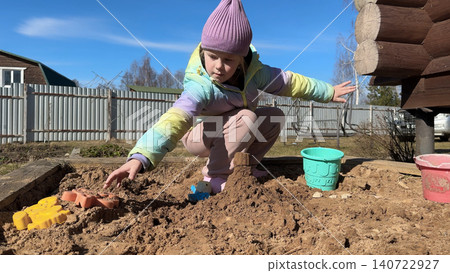 With sandy fingers and a big smile, the little girl decorates her newly built sandcastle with small pebbles and leaves she found nearby. 140722927