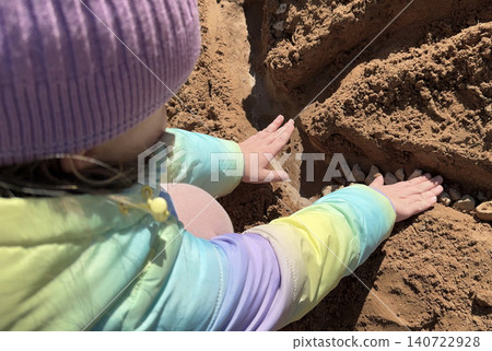 With sandy fingers and a big smile, the little girl decorates her newly built sandcastle with small pebbles and leaves she found nearby. With sandy fingers and a big smile, the little girl decorates her newly built sandcastle with small pebbles and leaves she found nearby. 140722928