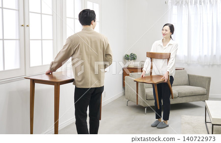 A couple carrying a table during a room makeover. A couple carrying a table during a room makeover. 140722973
