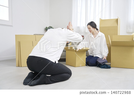 搬家時，一名男子深深鞠躬道歉，而一名女子正在收拾行李。 140722988
