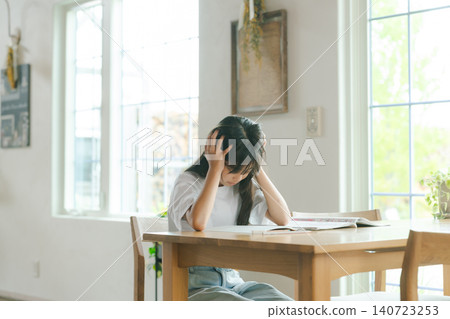 Girl holding her head while studying Girl holding her head while studying 140723253