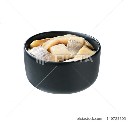 pieces of herring fillet on a black bowl isolated on a white background. pieces of herring fillet on a black bowl isolated on a white background. 140723803