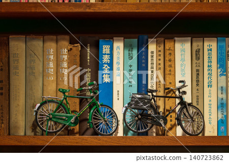 復古木質書架上的老舊書籍與精緻腳踏車模型 復古木質書架上的老舊書籍與精緻腳踏車模型 140723862