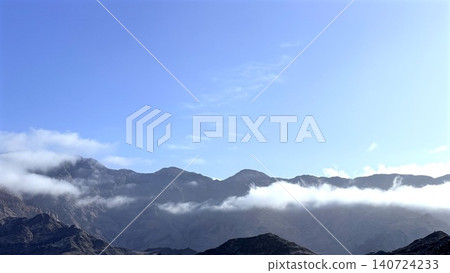 Mountain range with low clouds under clear blue sky Mountain range with low clouds under clear blue sky 140724233