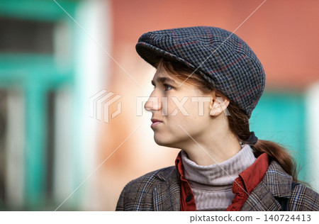 Woman in flat cap and plaid blazer looking aside. Profile portrait of young female in vintage tweed newsboy hat, retro style fashion, autumn outfit and urban lifestyle concept 140724413