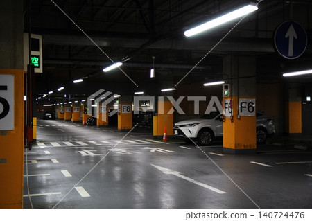 A dimly lit walkway with a pedestrian crossing in a multi-story parking garage. A dimly lit walkway with a pedestrian crossing in a multi-story parking garage. 140724476