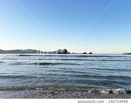 Waves crashing against the shore and a cloudless blue sky. 140724498