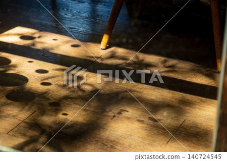 A close-up of the beautiful interplay of light and shadow as afternoon sunlight filters through the leaves and falls onto the warm wooden floor of the room. A close-up of the beautiful interplay of light and shadow as afternoon sunlight filters through the leaves and falls onto the warm wooden floor of the room. 140724545