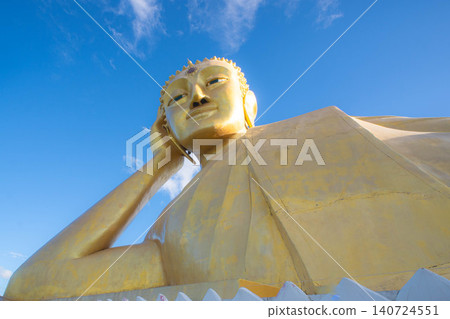 Low angle shot of giant golden reclining Buddha statue with moving clouds, Thailand. Low angle shot of giant golden reclining Buddha statue with moving clouds, Thailand. 140724551
