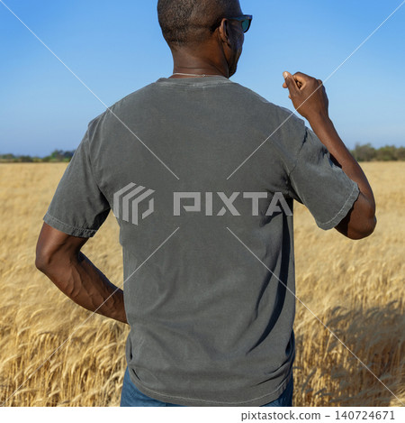 Blank washed grey t-shirt mockup on black man in wheat field at sunset, back view with copy space 140724671